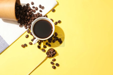 Foto de Granos de café vertidos de una taza, una taza de café negro sobre un fondo amarillo. El café contiene cafeína que previene la somnolencia. Espacio libre para el diseño. - Imagen libre de derechos
