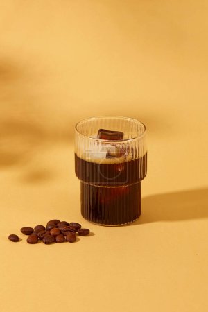 Téléchargez les photos : Gros plan d'une tasse de café noir avec des grains de café sur la table. Espace de copie pour publicité. Le café a la capacité d'aider le corps à réduire le risque de certains cancers. - en image libre de droit