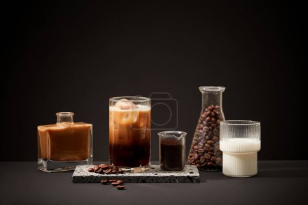 Téléchargez les photos : Les ingrédients pour faire du café au lait sont affichés sur un fond noir. La consommation à long terme de café caféiné a été associée à une réduction du risque de prédiabète et de diabète. - en image libre de droit