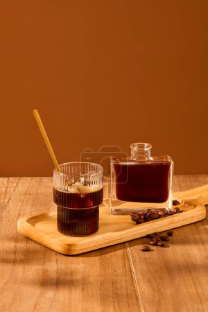 Foto de Una taza y una botella de café se muestran en una bandeja de madera con granos de café. Mesa de madera con fondo marrón. Exquisito espacio para la publicidad. - Imagen libre de derechos