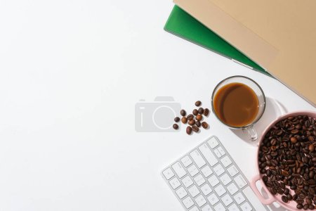 Foto de Granos de café en una bandeja de cerámica rosa, un teclado y una taza de café sobre un fondo blanco. Espacio libre para el diseño. Beber café ayuda a alertar a la mente. - Imagen libre de derechos