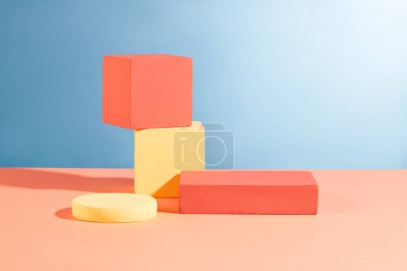 Téléchargez les photos : Une pile de deux podiums en cube disposés avec des podiums ronds et rectangle sur le dos bleu. Composition abstraite dans un design minimal - en image libre de droit
