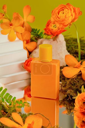 Téléchargez les photos : Gros plan d'un flacon de parfum d'orange sur fond de fleurs vibrantes et de feuilles vertes. Maquette cosmétique pour la publicité. Étiquette vierge pour le design. - en image libre de droit