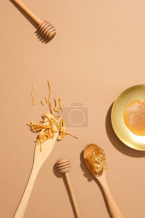Téléchargez les photos : Fond beige avec un plat de miel, cire d'abeille, cordyceps et deux gouttes de miel. Pose plate. Espace libre pour la présentation de produits biologiques - en image libre de droit