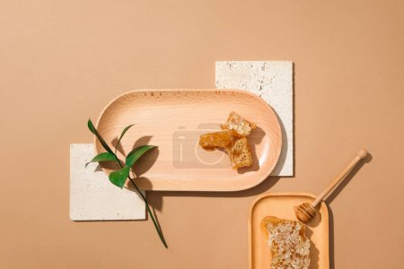 Foto de Un plato de madera con cera de abejas y hojas verdes. Cera de abejas en otro plato con un goteo de miel que se muestra. Producto de belleza extraído de la publicidad de miel - Imagen libre de derechos