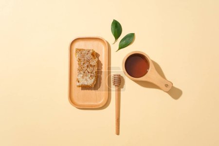 Foto de Cera de abejas fresca expuesta en un plato de madera, decorado con un goteo de miel y un tazón de miel. Los antioxidantes en la miel ayudan a bajar la presión arterial - Imagen libre de derechos