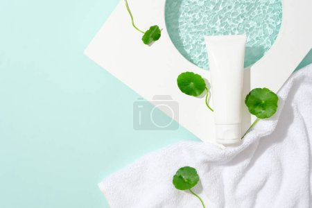 Photo for A cosmetic tube is placed on a platform, surrounded by pennywort leaves. Gotu kola helps reduce inflammation and redness caused by problems such as acne, skin infections, or skin irritation. - Royalty Free Image