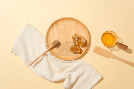Photo for Top view of beeswax, honey, a towel and props on a minimalist background. Honey has many uses in manufacturing and food. Copy space for advertising products with natural ingredients. - Royalty Free Image