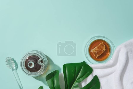 Photo for Honey is stored in glassware, green leaves and a towel are placed on a blue background. Empty space for product display and typography. Top view. - Royalty Free Image