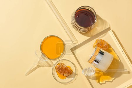 Téléchargez les photos : Vue de dessus d'un bocal cosmétique au design luxueux et miel stocké dans de la verrerie sur un fond beige. Cosmétiques naturels à l'extrait de miel. - en image libre de droit