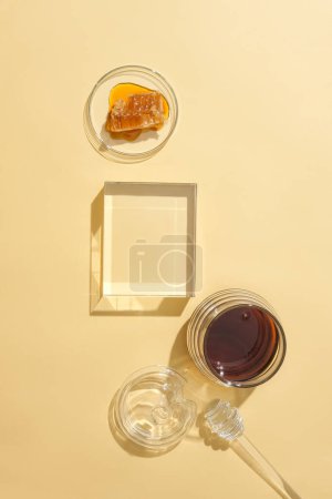 Photo for A blank glass podium is placed on a pastel background for product display. Honey is stored in glassware. Honey helps speed up the recovery of skin cells - the main cause of eczema. - Royalty Free Image