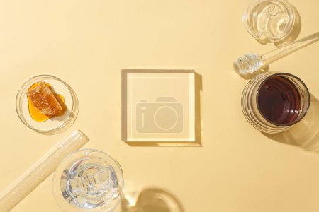 Foto de La cristalería se muestra sobre un fondo beige con miel. La miel estimula la piel para producir colágeno, creando suavidad para la piel y neutralizando los radicales libres. - Imagen libre de derechos