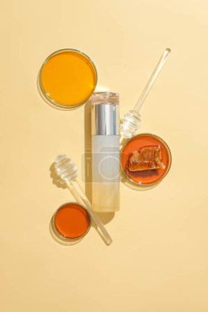 Photo for The honey was stored in petri dishes, two honey drizzles and an unlabeled cosmetic bottle. Honey slows down the aging process, limiting the appearance of wrinkles on the skin. - Royalty Free Image