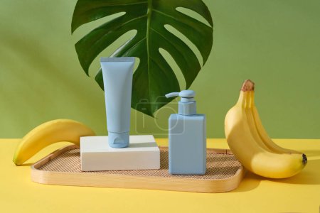 Blue pump bottle and tube without label are arranged on bamboo tray. Natural beauty blank label for branding mock-up concept of Banana (Musaceae) extract
