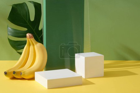 Téléchargez les photos : Concept de beauté bio avec podium vide dans différentes formes et un bouquet de bananes jaunes. Produit extrait Banane (Musaceae) peut vous aider à vous débarrasser de la peau sèche ou des taches sombres - en image libre de droit