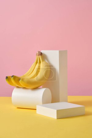 Photo for A set of white geometric shaped podiums placed on yellow plane with pastel pink background. Banana (Musaceae) contains nutrients that combat wrinkles and prevent fine lines - Royalty Free Image