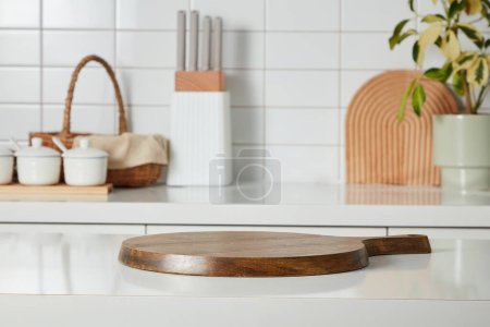 Kitchen interior shot with wooden cutting board, knife tray, spice boxes, bamboo basket and a small potted on white tile wall background. Blank space for display products, place your design and text.
