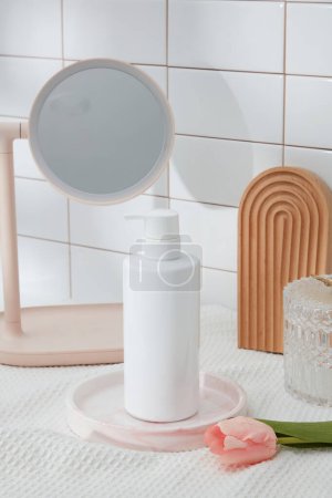 Foto de Fondo creativo para la presentación de productos cosméticos con concepto de baño: maqueta de botella blanca para la exhibición de champú o gel de ducha en la pared de azulejos con espejo, toalla y flor rosa. Publicidad foto - Imagen libre de derechos