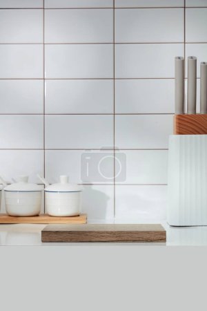 Kitchen interior decorated on white tile background - spice box, knife tray and an empty wooden podium for display product. Blank minimal scene with kitchen background for advertising product.
