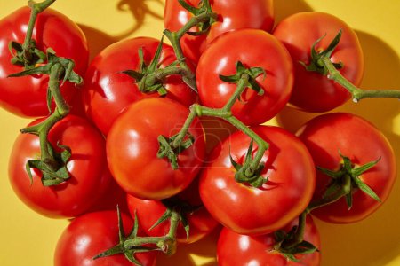 Kreative Kosmetik lag flach mit Tomatenzutat. Draufsicht auf frische Tomaten mit grünem Blattstiel auf gelbem Hintergrund. Tomaten haben viele Nährstoffe, die gut für die Gesundheit sind