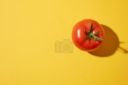 Top view of a red ripe fresh tomato on a yellow background. Blank space for text and design. The nutritional composition of tomatoes can protect the body from many dangerous diseases.