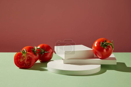 Front view of fresh tomatoes decorated with white podiums on a pink background. Minimal scene with copy space for cosmetics, business branding and product presentation