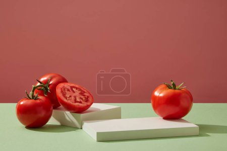 Cilindro podios blancos decorados con tomates frescos maduros sobre fondo rosa. Escena de presentación mínima del producto en pantalla vacía. Concepto de fruta de verano.