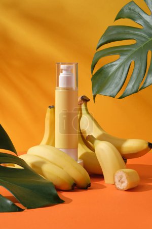 Photo for Mockup scene for advertising cosmetic of banana extract - pump bottle unbranded surround by ripe yellow bananas and green monstera leaves on a yellow background with leaf shadow - Royalty Free Image