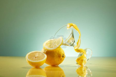 Téléchargez les photos : Tranches fraîches de citron et de citron décorées avec une tasse en verre et une écorce de citron sur fond rétro-éclairé. Scène pour un produit commercial comportant un composant citron - en image libre de droit