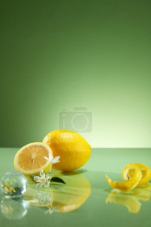 Foto de Una vista frontal de la cáscara y mitades de limón, flor blanca y bola de cristal decoradas sobre fondo verde. Escena mínima con espacio en blanco para mostrar su producto - Imagen libre de derechos