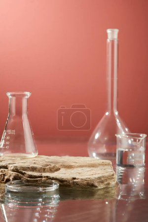 Photo for Front view of laboratory equipments placed on surface water and stone podium form an empty for cosmetic product presentation. Pink background for advertising with lab concept - Royalty Free Image
