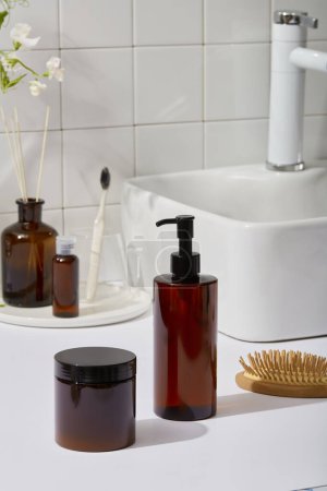 Photo for Bathroom concept with amber bottles unlabeled, wooden brush, reed diffuser and toothbrushes decorated on wash basin shelf. Mockup scene for cosmetic product for body care. Daily routine content. - Royalty Free Image