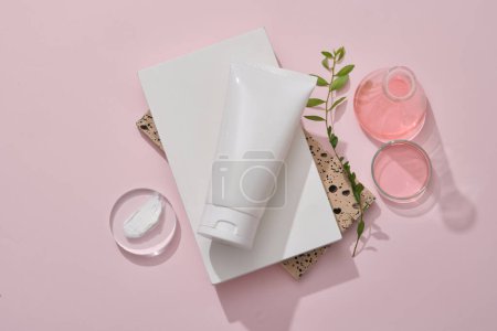 Photo for A white plastic tube mockup for cosmetic placed on stacked of white podium and bricks. Lab glassware containing pink liquid and cream texture on podium decorated on pink background - Royalty Free Image