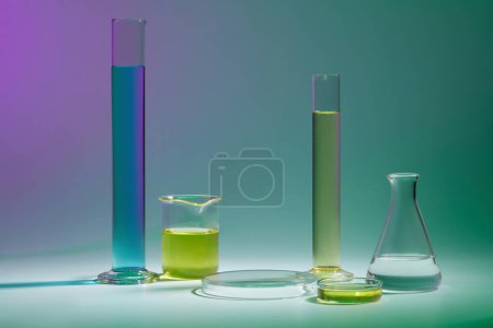 Foto de Fondo abstracto con concepto de laboratorio - cristalería de laboratorio que contiene líquido de color y podio transparente redondo para la presentación del producto cosmético sobre fondo de color. - Imagen libre de derechos