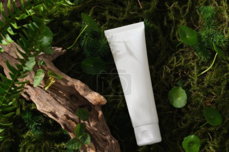 White plastic bottle unbranded placed on moss background with dry twig, fern, centella and green leaves. Natural concept for advertising and product promotion, mock up