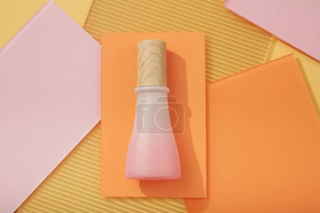 Téléchargez les photos : Une bouteille rose dégradé avec capuchon en bois sans étiquette décorée sur des feuilles acryliques colorées. Art minimaliste arrière-plan pour la publicité. Maquette d'emballage, design cosmétique - en image libre de droit