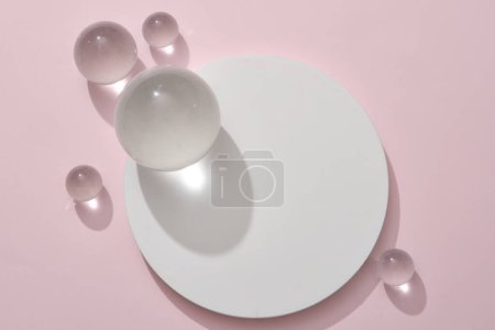 Foto de Podio redondo blanco decorado con algunas bolas de vidrio sobre fondo rosa pastel. Pedestal para productos cosméticos y maquetas de embalaje presentación de pantalla - Imagen libre de derechos