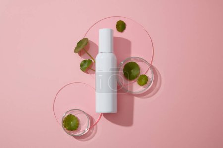 Photo for White mockup bottle for branding with fresh gotu kola leaves decorated on petri dish and round acrylic sheet on pink background. Space for presentation cosmetic of centella extract - Royalty Free Image