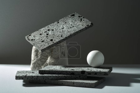 The dark rectangle stones stacked, gray rock and white ball decorated on black background. Blank space for cosmetic product presentation. Front view, minimal concept.