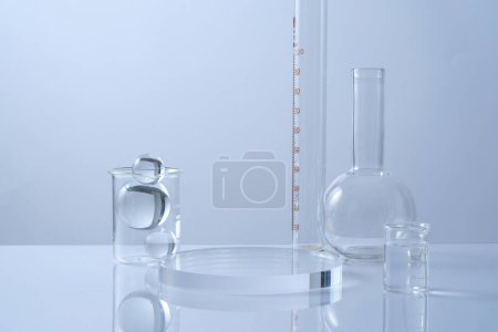 An empty transparent podium, glass balls and lab glassware decorated on white background. Minimal background with copy space for cosmetics and product presentation. Laboratory concept
