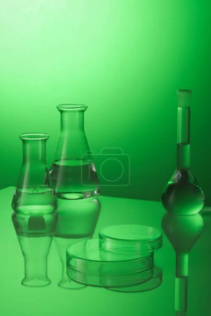 Minimal background with boiling flask and erlenmeyer flask containing transparent liquid inside and petri dishes upside down form an empty platform to display products. Laboratory concept.