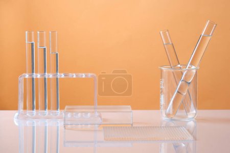 Foto de Vista frontal de podio cilíndrico transparente y cristalería de laboratorio que contiene líquido incoloro sobre fondo de color. Espacio en blanco para el producto cosmético de la exhibición con concepto mínimo. - Imagen libre de derechos