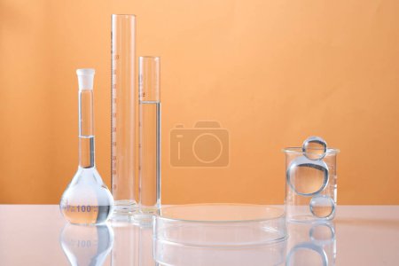 A petri dish upside down form an empty platform to display product and lab glassware, glass ball decorated on color background. Science laboratory research and development concept