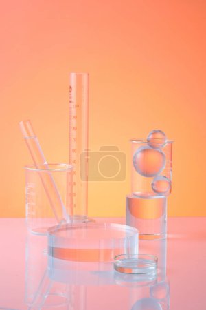 Lab theme with test tubes, beaker, petri dish and glass ball decorated on orange background. An empty transparent podium for display cosmetic product. Science and medical background