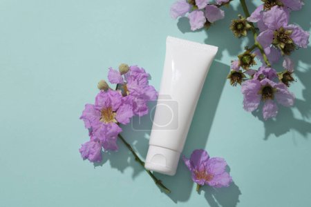 Cosmetic brand mockup on pastel background, surrounded by beauty purple flower. Plastic bottle unbranded for skin care. Packaging for cream, lotion, gel. Space for design