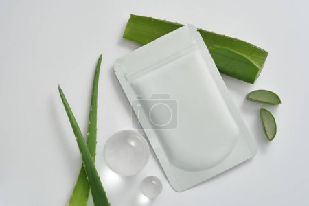 Photo for Branding and packaging mockup with facial sheet aloe vera mask package, aloe vera leaves and glass balls decorated on white background. Beauty product packaging design templates based on aloe vera - Royalty Free Image