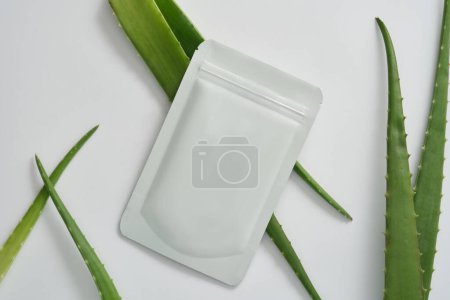 Photo for Sheet mask and aloe vera leaves on white background. Aloe vera extract is often used as a mask with many uses such as moisturizing, whitening, soothing the skin and preventing aging. - Royalty Free Image