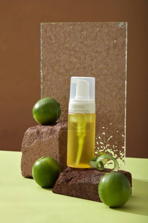 An empty spray bottle unbranded on stone podium, fresh lime citrus and acrylic sheet decorated on brown background. Mockup scene for cosmetic product of lime extract. Space for design.
