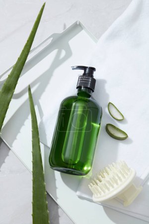 Photo for Mockup for shampoo product with green bottle unlabeled, comb, towel and fresh aloe vera on white background. Aloe vera contains many amino acids and proteolytic enzymes, vitamin that are good for hair - Royalty Free Image