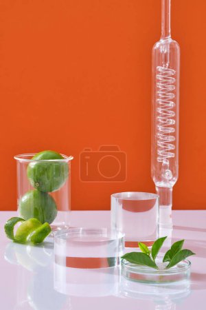 Scene for advertising cosmetic of lime extract with laboratory concept. Transparent podium, fresh limes in beaker and leaves in petri dish decorated on orange neon background.